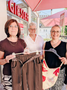 Drei lächelnde Mitarbeiterinnen von Mode Giesler präsentieren Sommermode vor dem Geschäft in Zell am HarmersbachDrei lächelnde Mitarbeiterinnen von Mode Giesler präsentieren Sommermode vor dem Geschäft in Zell am Harmersbach
