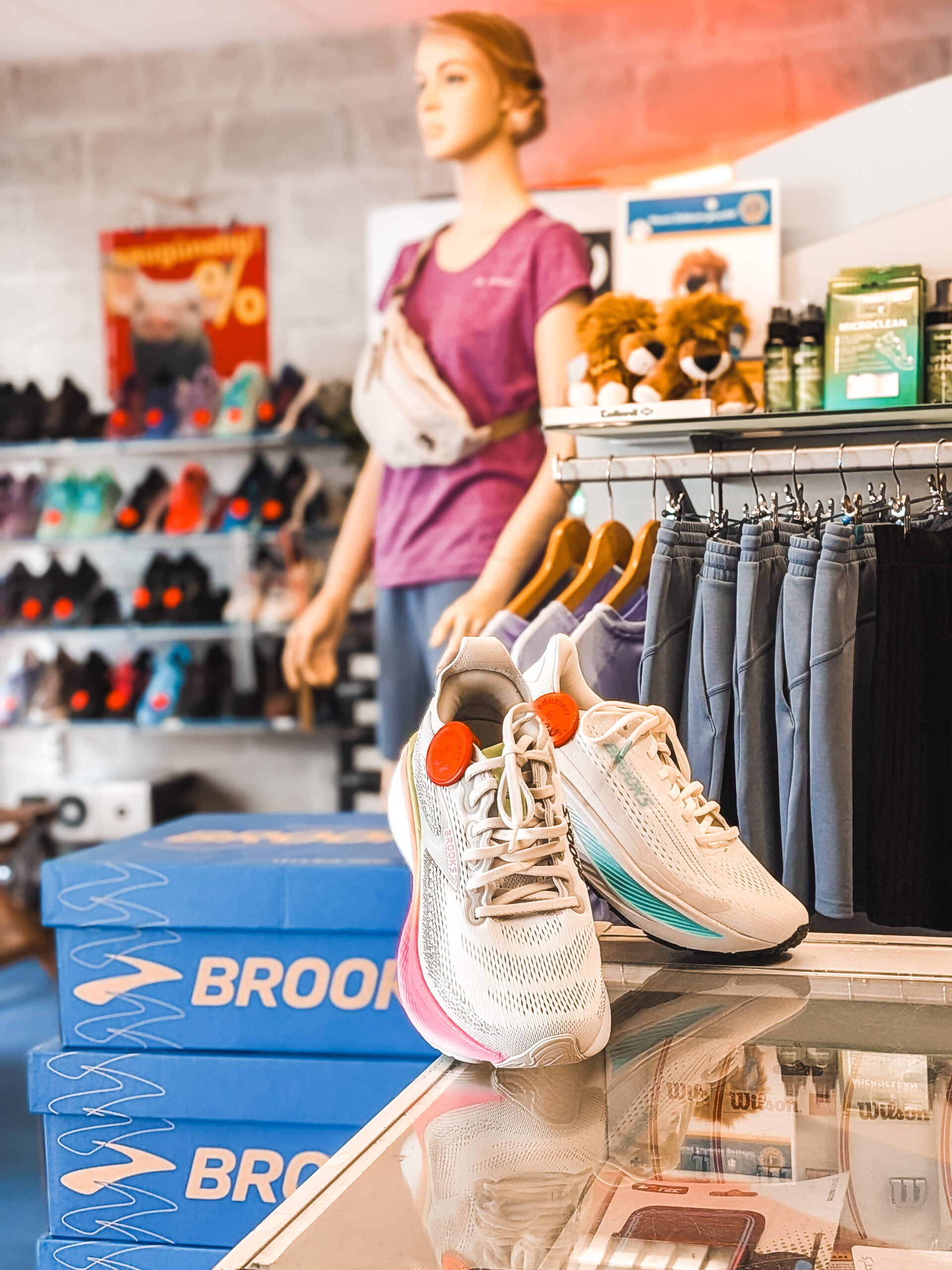 Reduzierte Brooks-Laufschuhe mit Rabatt-Etikett auf Schuhkarton bei Schuhhaus Beck, im Hintergrund Sportbekleidung und Schuhregal