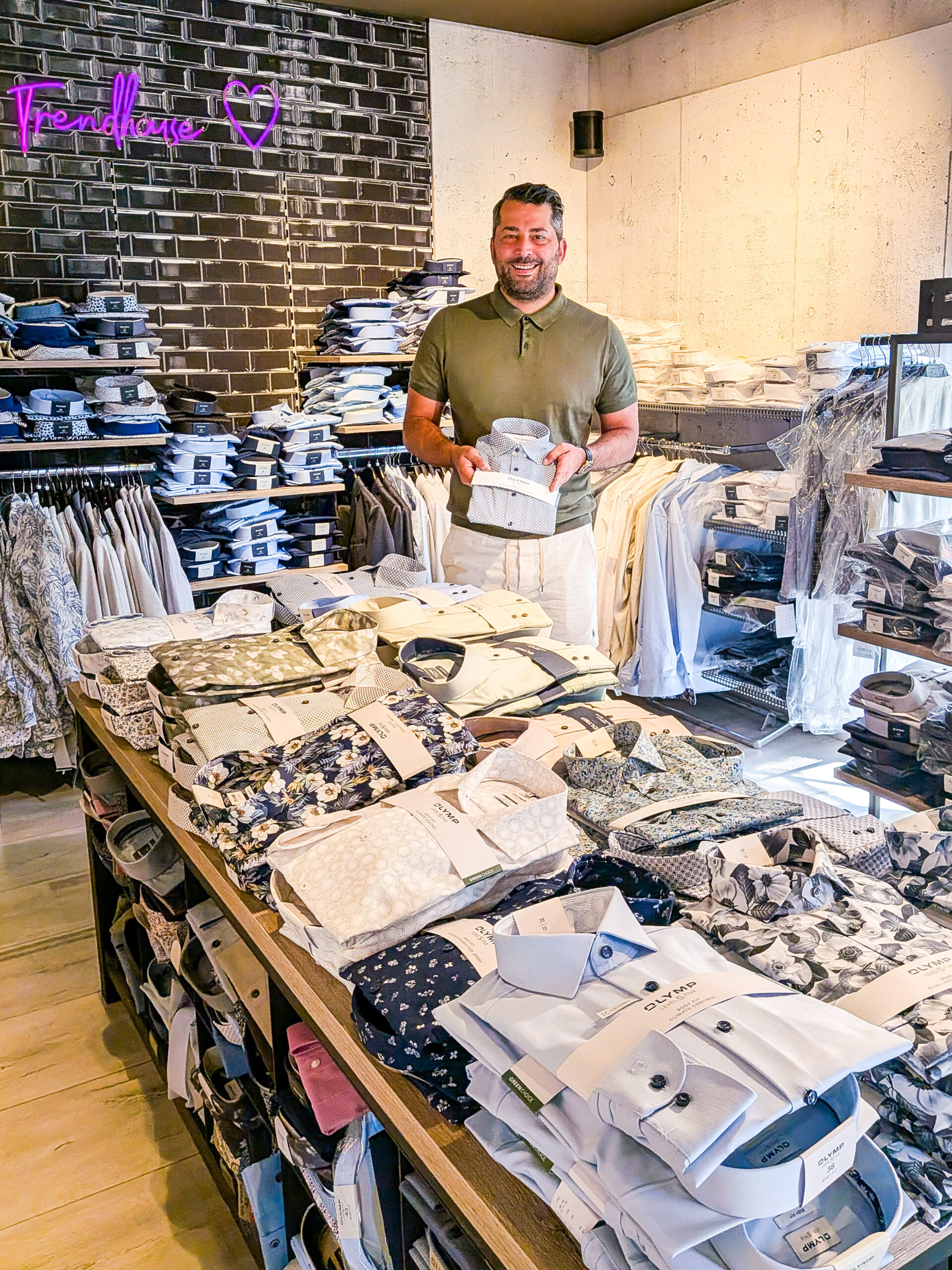 Volkan Sünger im Trendhouse Zell präsentiert Olymp-Hemd inmitten großer Auswahl an gefalteten Sommerhemden